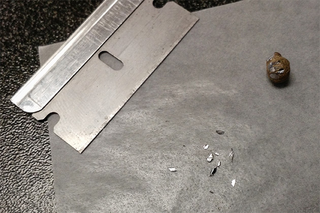 Shaving lead flakes off a fishing weight to test for lead removal